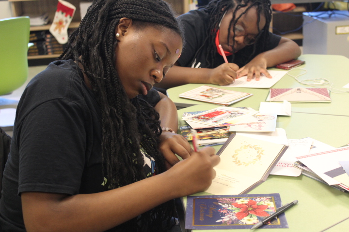 Stalia Edouard and Shana Daleus write holiday greetings to veterans.